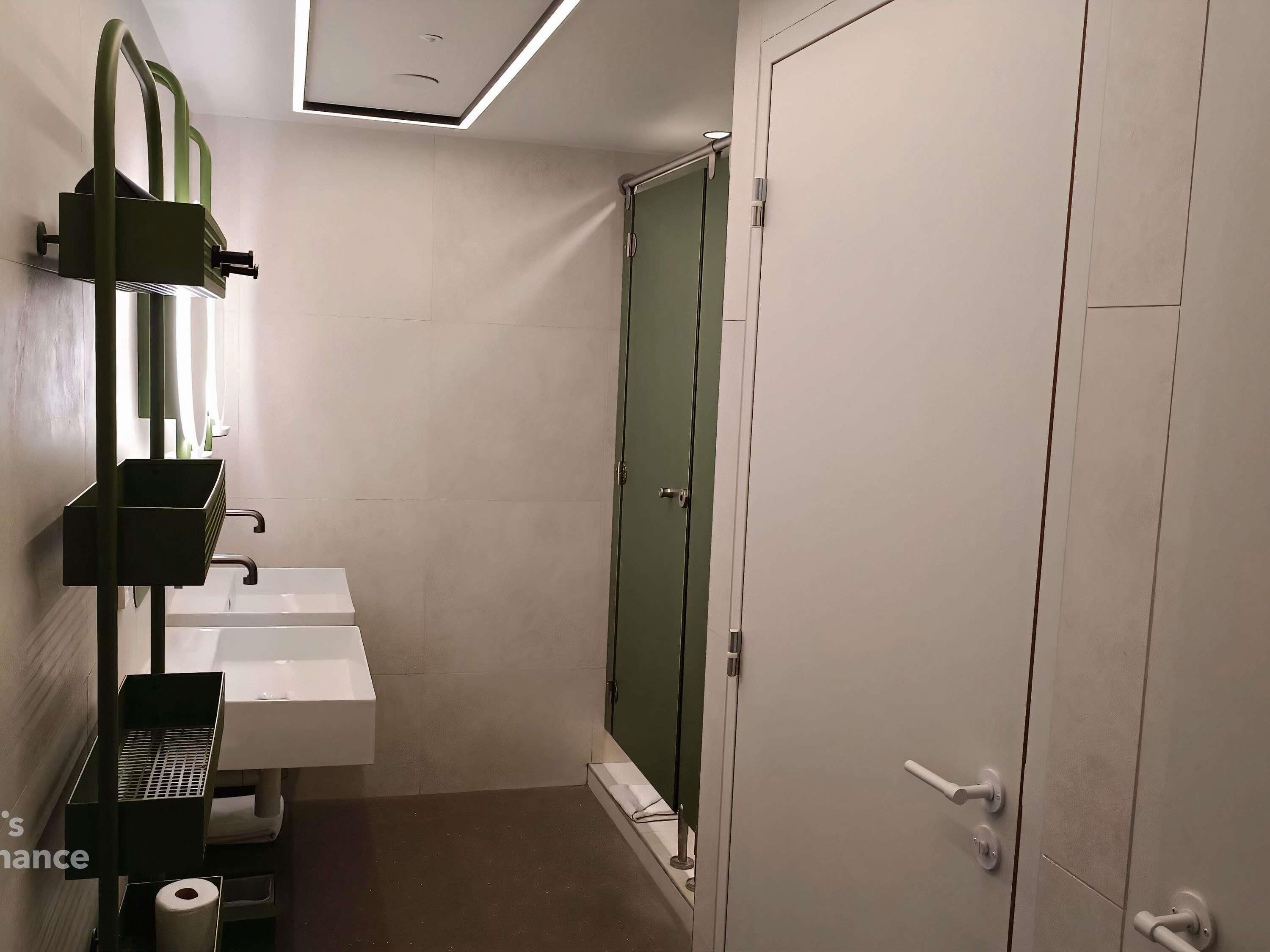 Een badkamer met een witte wasbak, een groene deur en een toilet.