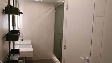 Een badkamer met een witte wasbak, een groene deur en een toilet.