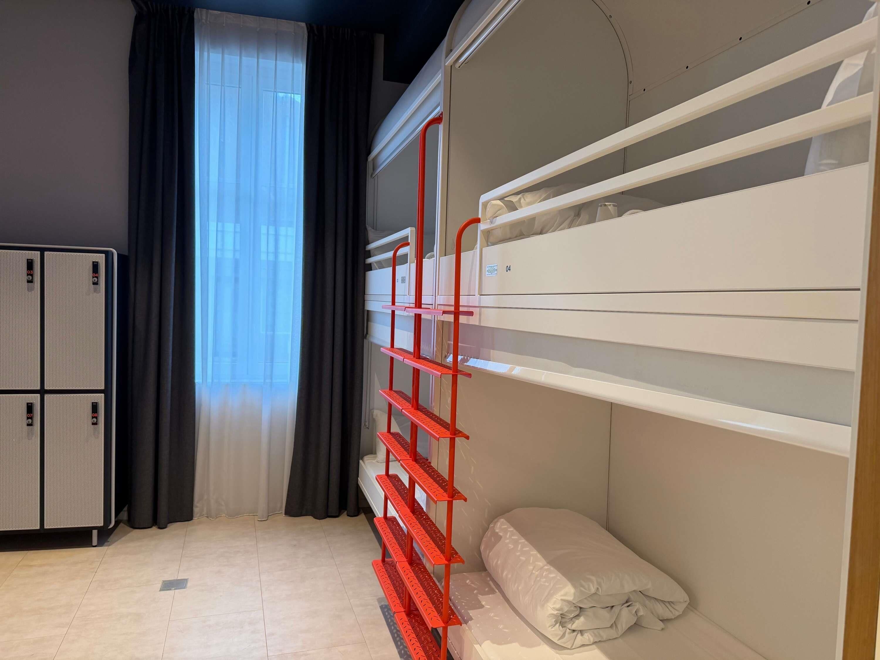 Ein Zimmer mit einem Etagenbett, einem Kleiderschrank und einem fenster mit Vorhängen.