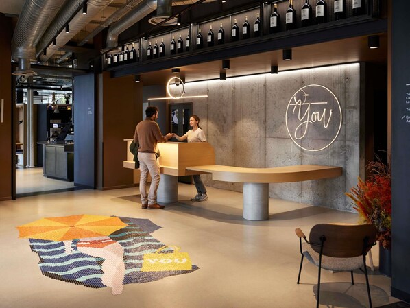 A reception desk with a neon sign, a patterned carpet, and a seating area with a chair.
