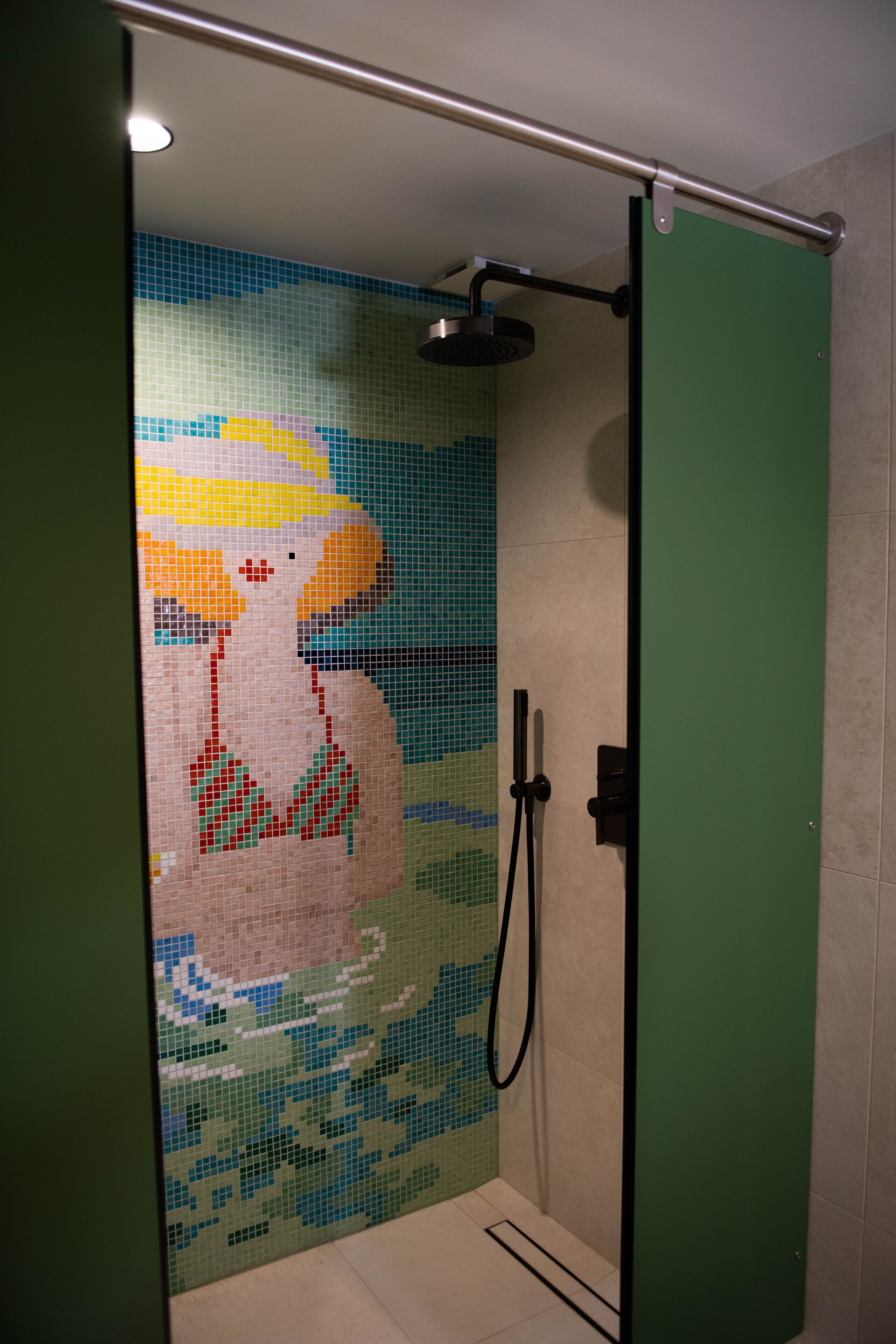 A shower with a mosaic tile wall and a green door.