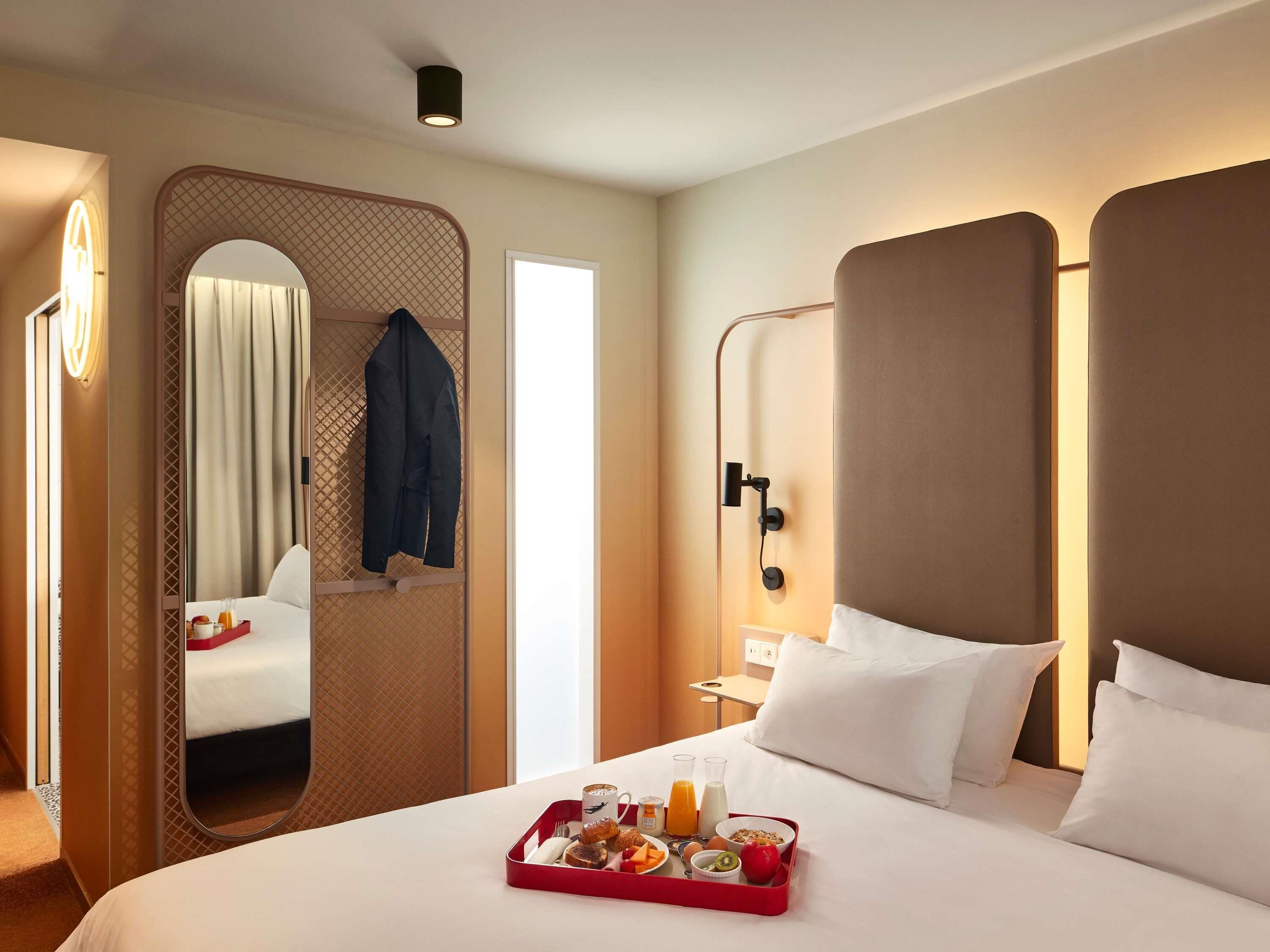Una habitación de hotel con cama, bandeja de desayuno, espejo y puerta.