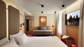 Una habitación de hotel moderna con una cama grande, un pequeño sofá, un televisor y un letrero de neón.