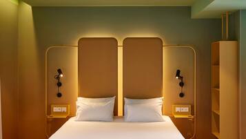 A hotel room with a large bed, two bedside tables, and a wardrobe.