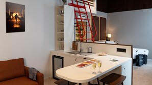 Una habitación de hotel moderna con kitchenette, comedor, sofá y cama.