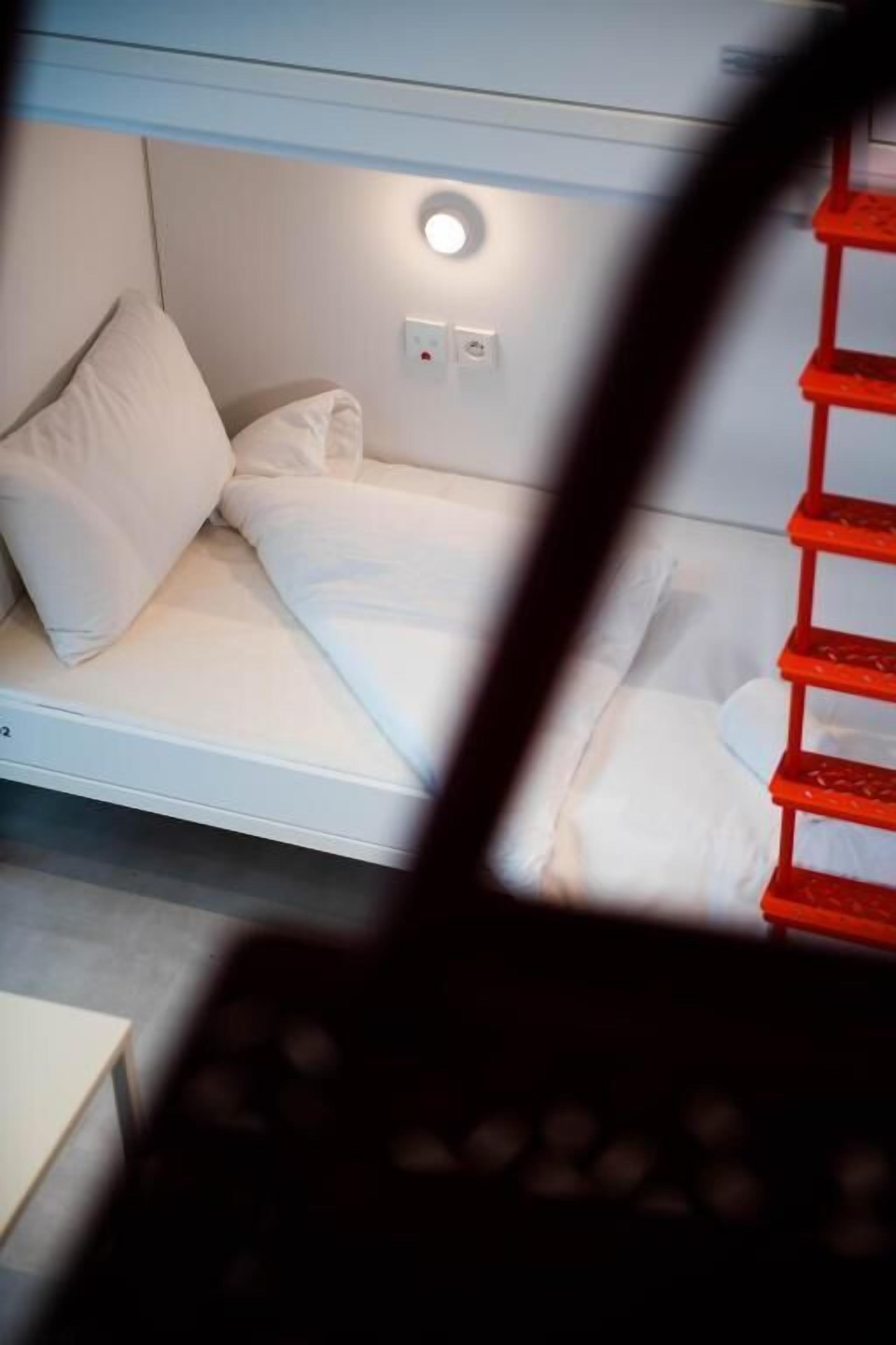 A bunk bed with white bedding and a small bedside table.