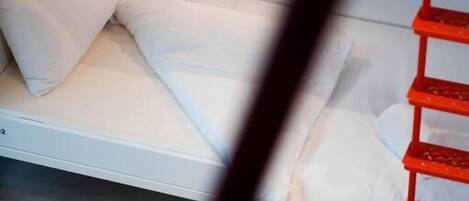 A bunk bed with white bedding and a small bedside table.