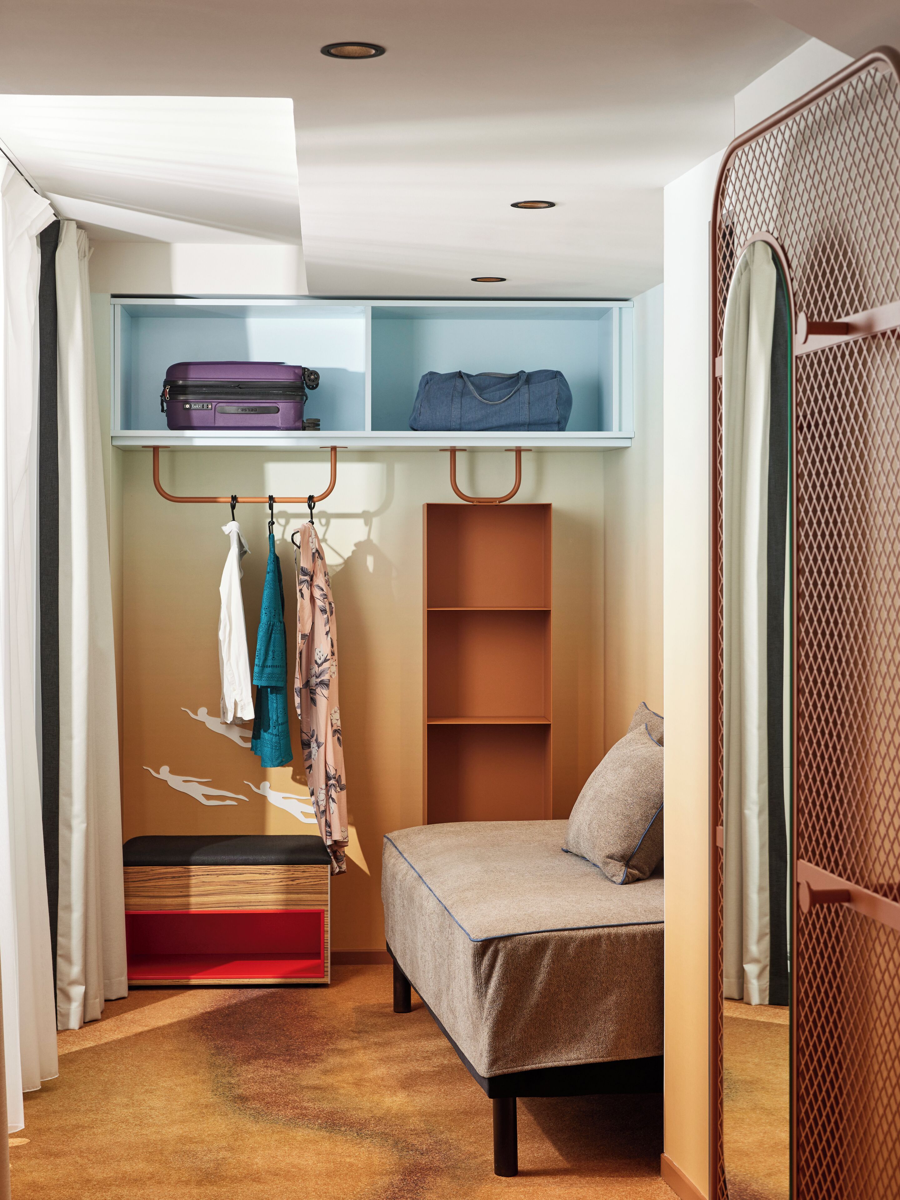 A compact bedroom with a bed, a wardrobe, and a small seating area.
