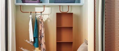 A compact bedroom with a bed, a wardrobe, and a small seating area.