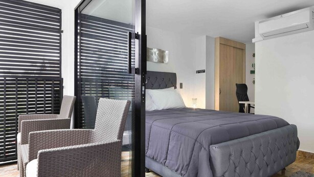 Een moderne slaapkamer met een bed, een stoel en een glazen deur naar een balkon.