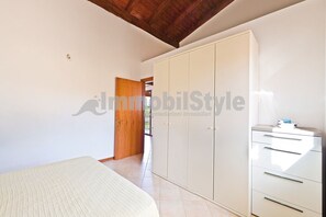 Un dormitorio con cama, armario y puerta de madera que da a otra habitación.