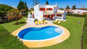 Une villa moderne dotée d’une piscine, d’un patio avec des chaises longues et d’un jardin bien entretenu.