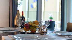 Taula de menjador preparada amb plats, coberts, un plat de fruita, copes de vi i un portavelis decoratiu.