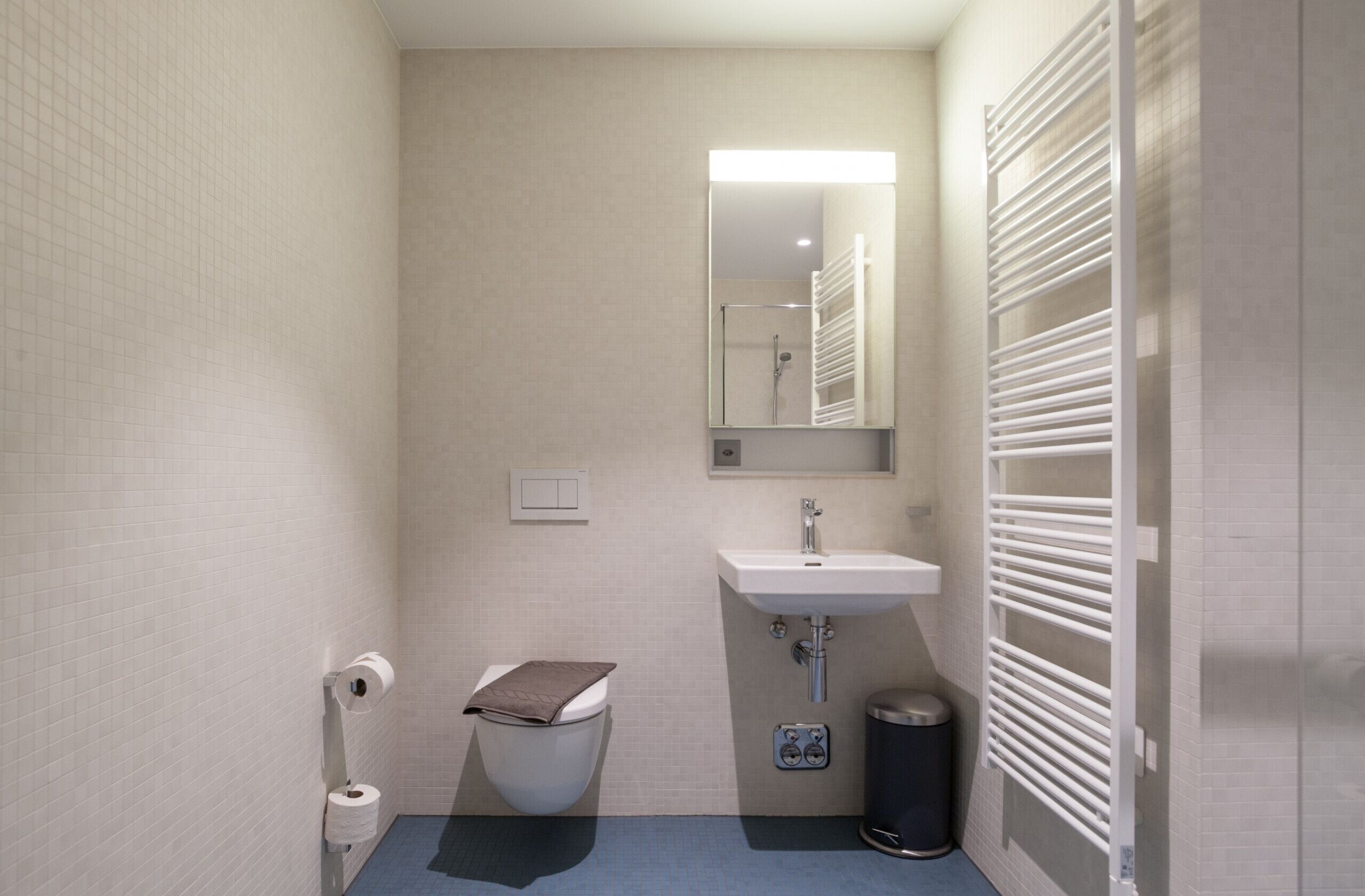 A small, compact bathroom with a toilet, sink, and mirror.