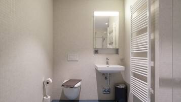 A small, compact bathroom with a toilet, sink, and mirror.