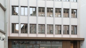Un edificio moderno con fachada plana, ventanas amplias y acceso a nivel de calle.
