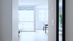 A bright, open hallway with wooden flooring leading to a balcony. - BS Fox I - Messe Hitrental Apartment (Basel)