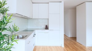 A modern kitchen with white cabinets, a stainless steel sink, and a small plant. - BS Fox I - Messe Hitrental Apartment (Basel)