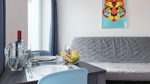 Un comedor con una mesa dispuesta para dos personas, una botella de vino y un cuenco de fruta.