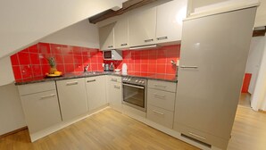 A kitchen with grey cabinets, a red backsplash, and a wooden floor. - ZH Strawberry - Oerlikon Hitrental Apartment (Zürich)