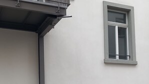 A building with a single entrance door, a small window, and a metal gate. - LU Station II - Hitrental Apartment (Lucerne)