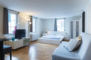 Une chambre moderne avec un lit, une table de chevet, une télévision et une vue sur la ville.