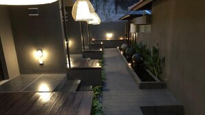A modern outdoor pathway with wooden flooring, recessed lighting, and planters with greenery. - Bali Elephants Boutique Villa (Jimbaran)