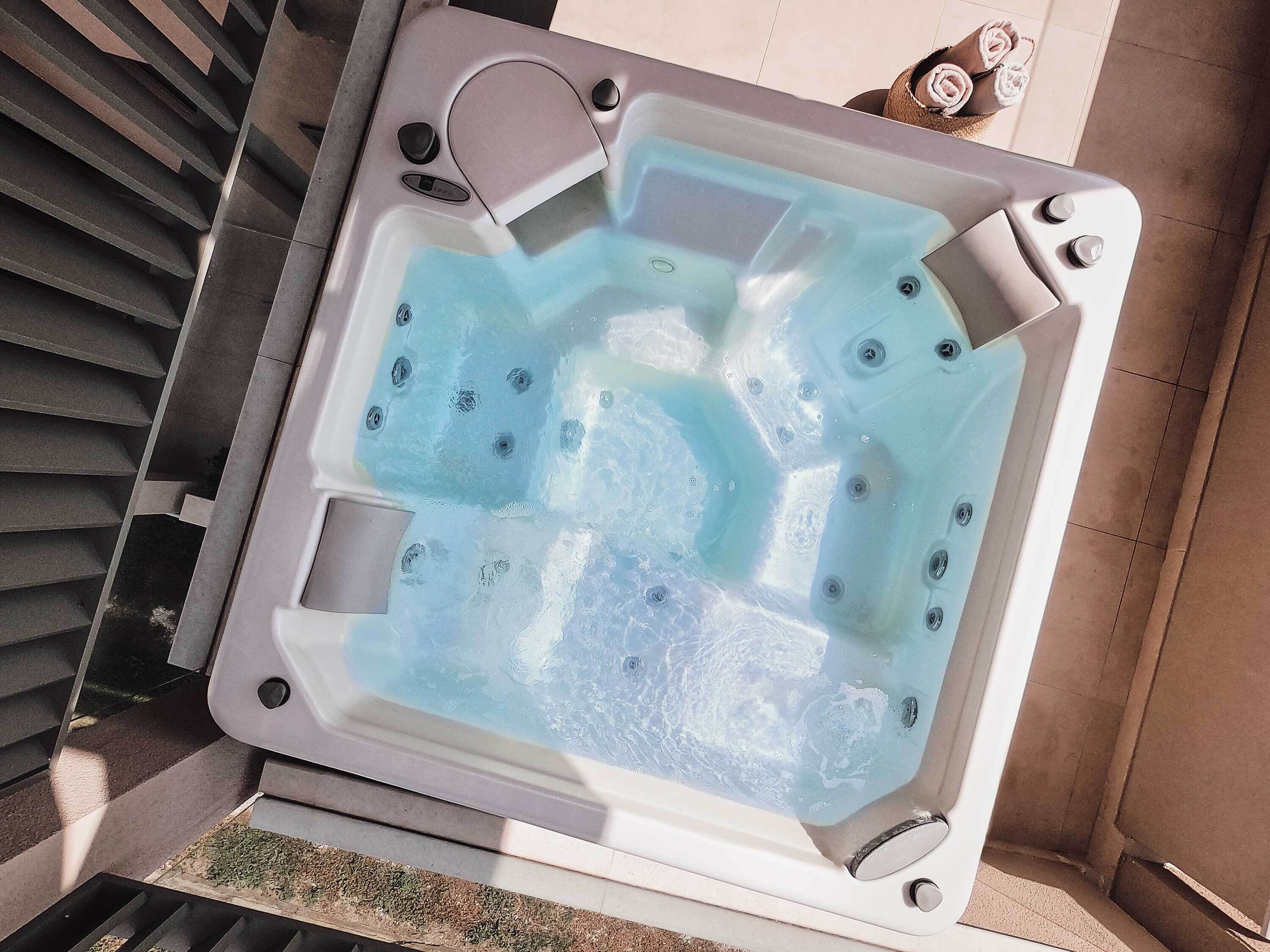 A hot tub with a rectangular shape, multiple jets, and a drain.