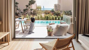 Una habitación moderna con un amplio ventanal corredero que da a una zona de piscina, una silla de madera y una pequeña mesa redonda con tazas.