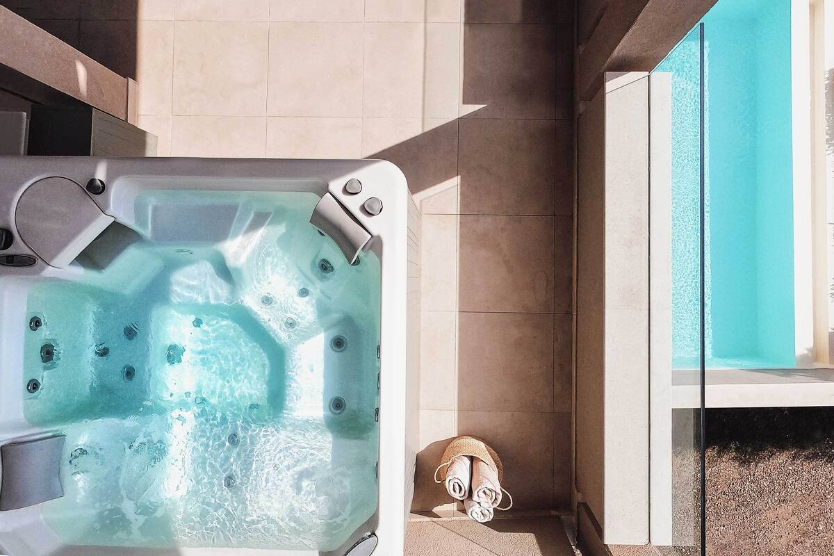 Un bain à remous avec jets, une serviette et une porte en verre donnant accès à une piscine.