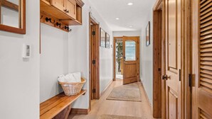 A hallway with wooden cabinets, a bench with a basket, and a door leading outside. - Summer Haven in Snowmass! Stunning Balcony Views, Pool/Hot Tub, Wood FP, Sleeping Den, W/D & Parking (Snowmass Village)