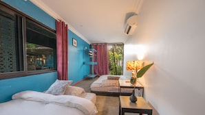 Quarto com duas camas, uma mesinha e uma janela com cortinas.