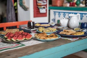 A table with various food items including watermelon slices, croissants, and bread. - Udaya Angkor Bed And Breakfast (Siem Reap)