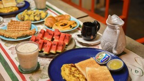 Uma mesa de café da manhã com waffles, torradas, ovos e um jarro de leite.