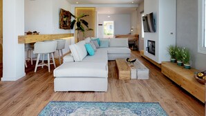 A modern living room with a white sectional sofa, wooden flooring, and a blue patterned rug. - Beachfront luxury villa with hot tub & sunset view (Chania)