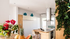 A modern kitchen with a wooden island, a built-in oven, and a window overlooking the garden. - Beachfront luxury villa with hot tub & sunset view (Chania)
