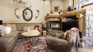 A cozy living room with a fireplace, a sofa, a coffee table, and a rug. - Beautiful Snowmass Getaway! Scenic Views, Balcony, Pool, Hot Tub, Gas FP, Elevator & Trail Access (Snowmass Village)
