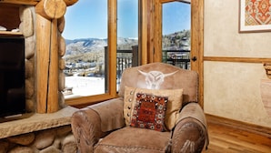 A leather armchair with a decorative pillow, positioned in front of a wooden-framed window with a mountain view. - Beautiful Snowmass Getaway! Scenic Views, Balcony, Pool, Hot Tub, Gas FP, Elevator & Trail Access (Snowmass Village)