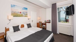 Habitación de hotel con cama, escritorio, silla, televisión y ventana con vistas.