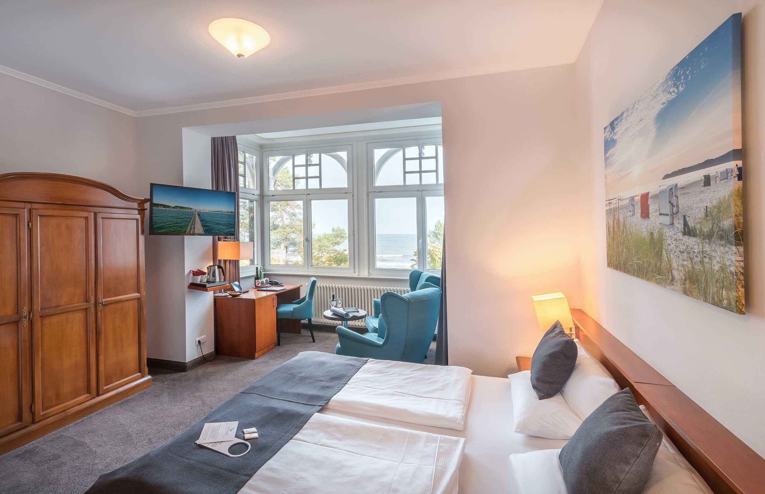 A hotel room with a bed, a desk, a chair, a television, and a large window with a view.