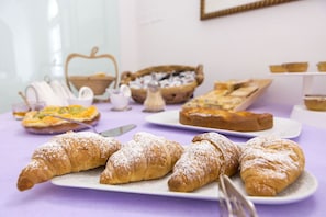 A table with various pastries and bread, including croissants and a basket of bread. - Villa Lupara (Salerno)