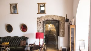 Una sala de estar con chimenea, un sofá verde, una lámpara roja y un aparador de madera.