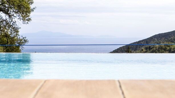 Una piscina con vista a una costa distante y montañas.