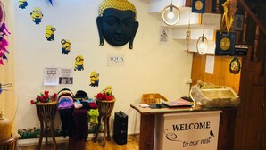Een gezellige kamer met een houten vloer, een welkom bord, een Boeddha-beeld en een muur versierd met Minion-stickers.