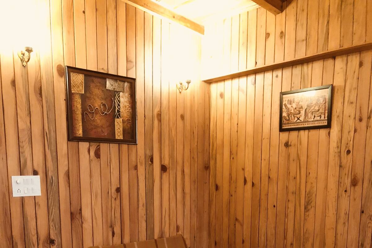 Een kamer met houten lambrisering, een bed, een ingelijst foto en een lichtschakelaar.