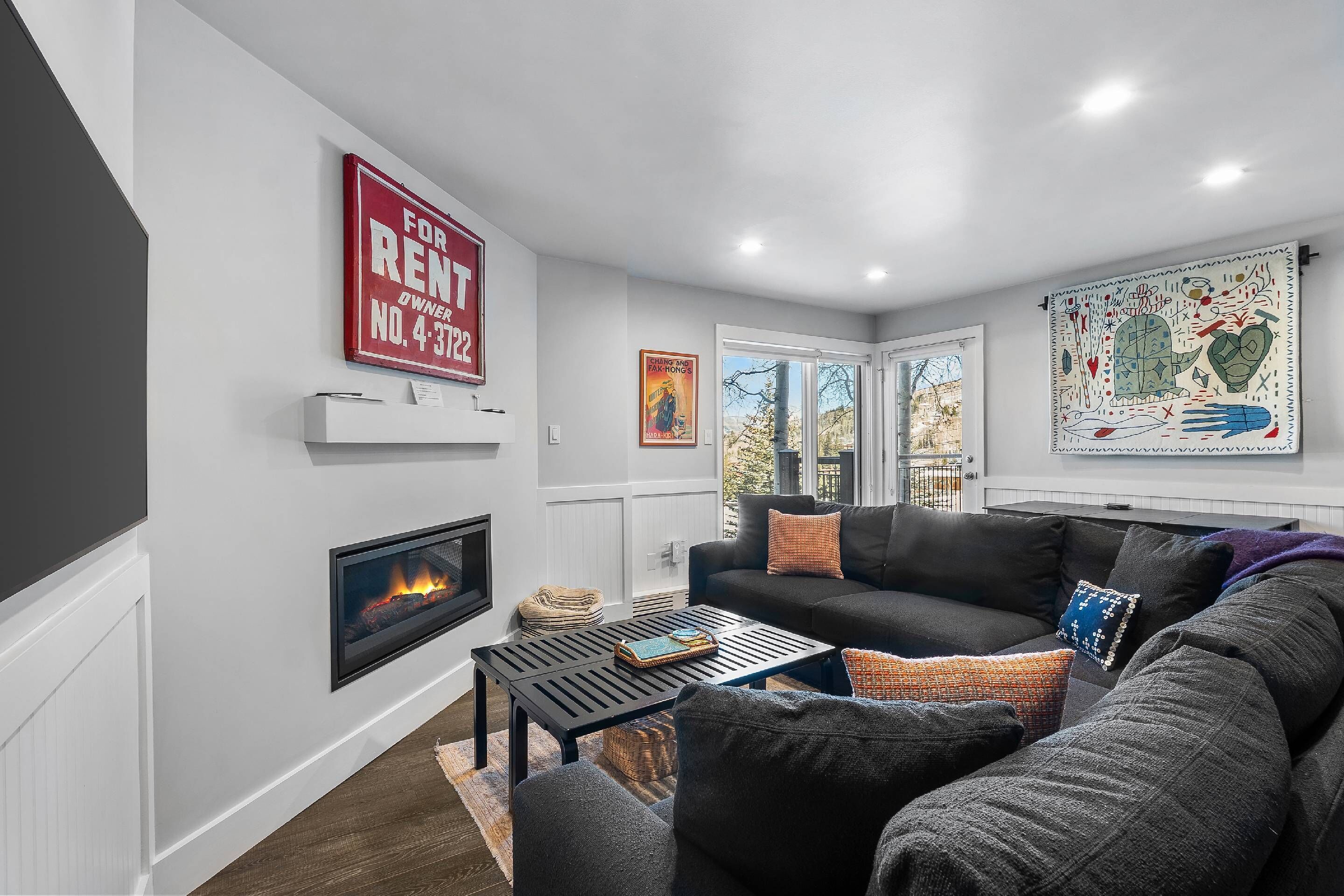 A modern living room with a fireplace, a black sofa, and a coffee table.