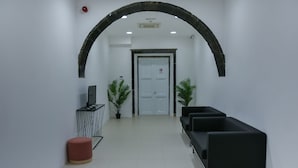 A reception area with a white door, black benches, potted plants, and a red stool. - Casa do Teatro (Ponta Delgada)