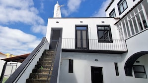 A white building with a balcony, a staircase, and a chimney. - Casa do Teatro (Ponta Delgada)