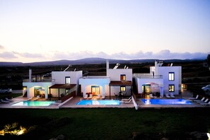 A modern two-story house with a swimming pool, outdoor seating, and a view of the mountains. - Nerida Beachfront Villas (Rhodes)