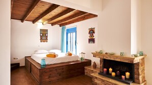 A bedroom with a wooden bed, a stone fireplace with candles, and a blue door. - Nerida Beachfront Villas (Rhodes)